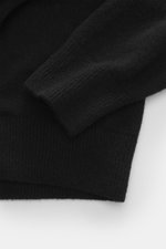 Close-up top-down view of Officine Générale Knitted polo 'Mark' black sleeve and hem, showing soft touch mix of wool, alpaca wool, silk, and cashmere with fine knit pattern, regular fit, skipper collar, and comfortable ribbed cuffs.