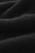Close-up from a side angle of Officine Générale Knitted polo 'Mark' black, showing fine knit pattern, soft touch, and fabric texture with wool, alpaca wool, silk, cashmere, regular fit, skipper collar, and ribbed cuffs.