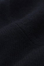 Nahaufnahme des feinen Strickbildes und weichen Griffs vom navyfarbenen FTC Cashmere Troyer, fotografiert aus schräger Perspektive.
