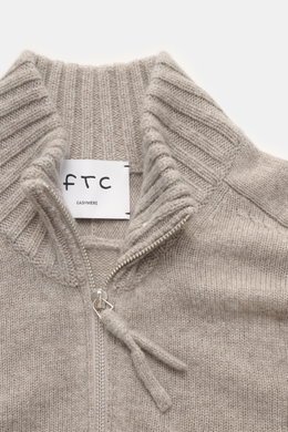 Nahaufnahme aus leichter Draufsicht des FTC Cashmere Troyer sand meliert mit Troyer-Kragen, Reißverschluss, feinem Strickbild und weichem Griff.