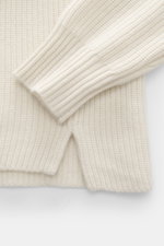 Nahaufnahme des FTC Cashmere Troyer creme, fotografiert von oben, zeigt weiche, mittelgrobe Strickstruktur, Rippbündchen, Regular Fit und Troyer-Kragen mit Reißverschluss, reiner Cashmere für luxuriösen Komfort.