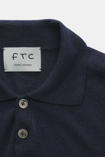 Nahaufnahme des FTC Strickpolo navy aus Cashmere und Lyocell, Slim Fit, klassischer Polokragen, Perlmuttknöpfe, feines Strickbild, von oben fotografiert.