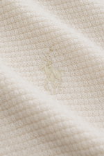 Nahaufnahme des Polo Ralph Lauren Troyer creme aus reiner Wolle mit markantem Strukturstrick und tonalem Polospieler-Stitching, Detailansicht.