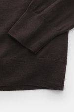 Close-up image of the B.F. Knitwear Merino knit polo dark violet sleeve and hem, photographed from a top-down perspective, showing a fine knit pattern, knit from pure merino wool with a soft feel, regular fit, classic polo collar, and flexible ribbed cuff
