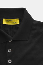 Close-up front view of B.F. Knitwear Merino knit polo black, knit from pure merino wool with soft feel, fine knit pattern, regular fit, classic polo collar, and flexible ribbed cuffs.