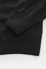 Close-up view of the sleeve and cuff of the B.F. Knitwear Merino knit polo black, showing fine knit pattern, soft feel, regular fit, classic polo collar, flexible ribbed cuffs, and knit from pure merino wool.