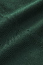 Nahaufnahme des dunkelgrünen von Braun Merino Feinstrickpolo mit feinem Strickbild, weichem Griff und Skipper-Kragen aus reiner Merinowolle.