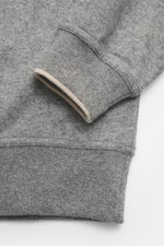 Close-up side view of the cuff and hem of the Brunello Cucinelli Cashmere quarter-zip jumper grey melange, showing pure cashmere fabric with fine knit, soft touch, narrow contrast edges, flexible ribbed cuffs, and regular fit. Sporty casual essential made