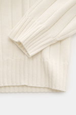 Close-up top-down view of the sleeve and hem of the Brunello Cucinelli Cashmere Knit Polo Cream, featuring pure cashmere, wide rib knit, soft touch, slim fit, knitted shark polo collar, two-button placket, and ribbed cuffs. Timeless essential for the refi
