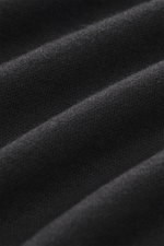 The Row Strickpolo 'Miranne' schwarz in Nahaufnahme, feines Strickbild, weicher Griff aus Kaschmir-Baumwoll-Mix, Detailfoto aus schräger Perspektive.