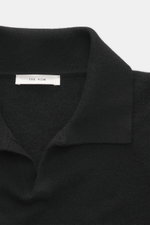 Nahaufnahme von The Row Strickpolo 'Ripley' schwarz, Polokragen mit offener Leiste, feines Kaschmir, Slim Fit, weicher Griff, komfortable Rippbündchen.