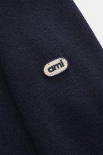 Nahaufnahme des Ami Paris Merino Troyer navy/rot in reiner Merinowolle mit weichem Griff, Logo-Patch am Ärmel, Regular Fit, Troyer-Kragen mit Zipper, farblich abgesetzte Ärmelabschlüsse, fotografiert von oben schräg.