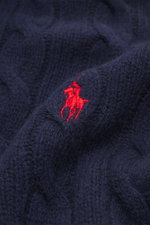 Close-up front view of Polo Ralph Lauren Troyer navy showing detailed cable knit wool with cashmere, soft texture, and red tonal Polo player stitching. An essential for cool days: This Troyer by POLO RALPH LAUREN impresses with high-quality cable knit woo