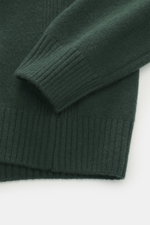 04651/ A trip in a bag Strickpolo dunkelgrün, Detailaufnahme des Ärmels und Saums aus Merinowolle und Cashmere mit Rippbündchen.