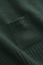 Nahaufnahme des dunkelgrünen 04651/ A trip in a bag Strickpolo aus Merinowolle und Cashmere, Detail Rippbündchen und feines Strickbild.