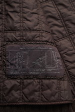 Nahaufnahme des dunkelbraunen, wattierten Innenfutters mit Anleitungsetikett der Stone Island Cashmere Strickjacke 'Ghost Piece' dunkelbraun.