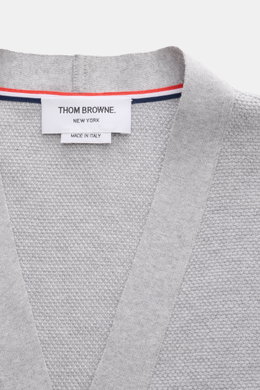Thom Browne Cardigan hellgrau meliert, Detailansicht von oben auf fein strukturierte Baumwoll-Strickqualität mit V-Ausschnitt, Tricolore-Ripsband und Markenlabel.