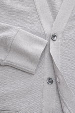 Nahaufnahme des Thom Browne Cardigan hellgrau meliert von oben, zeigt fein strukturierte Baumwolle mit Perlmuttknöpfen und flexiblem Ärmelbündchen.