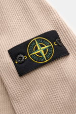Nahaufnahme der Stone Island Strickjacke 'Rib' beige mit klassischem Rippstrick-Design und Kompass-Badge am Ärmel aus reiner Baumwolle.