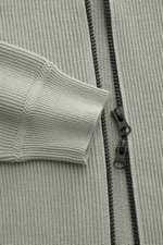 Nahaufnahme der Stone Island Strickjacke 'Rib' salbei, reine Baumwolle mit Rippstrick, Zwei-Wege-Reißverschluss und komfortablem Ärmelbündchen.