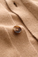 Close-up, angled view of the Fioroni Cashmere cardigan light brown mottled showing fine knit texture, smooth button placket with a brown button, and soft cashmere fabric. Exquisite craftsmanship from Italy: This cardigan by FIORONI is precisely made from 