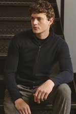 Mann sitzt seitlich auf Treppe, trägt von Braun Cashmere Strickjacke navy aus reinem Cashmere, Slim Fit, Stehkragen, Reißverschluss, weicher Griff.