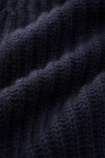Nahaufnahme des von Braun Cashmere Cardigan navy aus grobem Chunky-Knit Patentstrick mit weichem Griff, fotografiert aus schräger Perspektive.