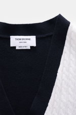 Nahaufnahme von Thom Browne Cardigan weiß/schwarz, fotografiert von oben, mit klassischem Zopfstrick, weichem Griff und vier Knöpfen.