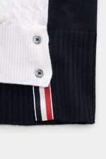 Nahaufnahme des Thom Browne Cardigan weiß/schwarz von oben, mit klassischem Zopfstrick, weichem Griff, Vier-Knopf-Leiste und kontrastfarbigen Streifen am Saum.