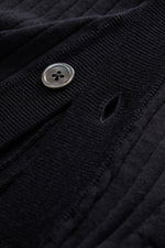 Nahaufnahme des Thom Browne Cardigan navy aus elastischer, fein gestrickter Wolle mit Knopf und Knopfloch, fotografiert aus schräger Perspektive.