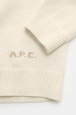 Nahaufnahme des Ärmels und Bunds des A.P.C. Cardigan 'Kevin' creme aus reiner Wolle mit kontrastfarbenem Logo, fotografiert von oben.