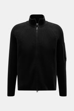 C.P. Company Strickjacke schwarz, frontale Nahaufnahme, mittelfeiner Baumwoll-Microfaser-Strick, Waffeloptik, Slim Fit, Zwei-Wege-Reißverschluss, Stehkragen, Oberarm-Zipper-Tasche, Linsen-Detail.