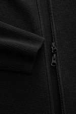 C.P. Company Strickjacke schwarz in Nahaufnahme, puristisches Design, Waffelstrick, YKK Zwei-Wege-Reißverschluss, Oberarm-Zipper, Stehkragen, Baumwolle/Microfaser, Slim Fit, mittelfein gestrickt.