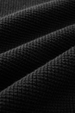 C.P. Company Strickjacke schwarz in seitlicher Frontansicht, puristisches Design, Waffelstrick, Slim Fit, Zwei-Wege-Reißverschluss, Stehkragen, Zipper-Tasche am Oberarm.