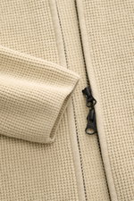 Nahaufnahme aus schräger Perspektive der sandfarbenen C.P. Company Strickjacke mit puristischem Design, markanter Waffelstrick-Optik, robustem Zwei-Wege-Reißverschluss und mittelfeinem Strickbild.