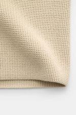 Nahaufnahme der sandfarbenen C.P. Company Strickjacke mit mittelfeinem Waffelstrickmuster, Baumwolle und Microfaser, Detailansicht von oben.