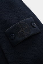 Close-up der Stone Island Strickjacke 'Ghost Piece' navy, Detailaufnahme des tonalen Badges am Oberarm, mittelfeines Strickbild, weicher Griff.