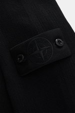 Nahaufnahme der schwarzen Stone Island Strickjacke 'Ghost Piece' mit tonalem Badge, mittelfeinem Strickbild und weichem Baumwoll-Cashmere-Mix aus seitlicher Perspektive.