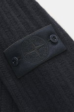 Nahaufnahme der Stone Island Strickjacke 'Ghost' navy, fotografiert schräg von oben, mit tonalem Kompass-Badge, Knöpfen und weichem Schurwoll-Cashmere-Mix.