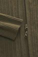 Nahaufnahme der Stone Island Strickjacke 'Ghost' oliv im Schurwoll-Mix, Fokus auf Reißverschluss und Rippbündchen, sportiver, wärmender Look.