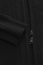 Nahaufnahme aus frontaler Perspektive der Stone Island Strickjacke 'Ghost' schwarz mit Zopfmuster, zwei-Wege-Reißverschluss und Rippbündchen, gefertigt aus Schurwolle-Cashmere-Mix, tonales Kompass-Badge am Oberarm sichtbar.