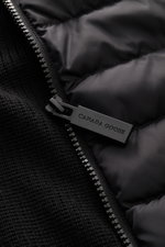 Nahaufnahme aus seitlicher Perspektive der Canada Goose Strickjacke 'Hybridge Knit' schwarz mit robustem Reißverschluss, Daunen-Front und Wollstrick.