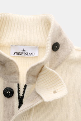 Close-up front view of the Stone Island Cardigan 'Lambswool' cream showing its warm wool blend knitwear, standing collar with buttoned tab, embossed buttons, felt details, and robust two-way zip. A stylish essential for cool days featuring distinctive pur