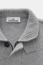 Nahaufnahme der Stone Island Strickjacke 'Lambswool' grau meliert, von oben fotografiert, mit Wollmix, Linksstrick, Knöpfen, Zipper, Filz-Details und Kompass-Badge.