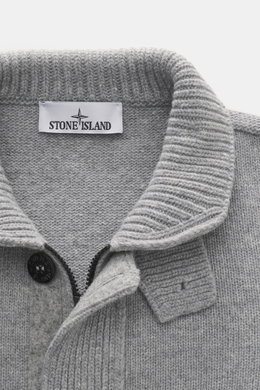 Nahaufnahme der Stone Island Strickjacke 'Lambswool' grau meliert, von oben fotografiert, mit Wollmix, Linksstrick, Knöpfen, Zipper, Filz-Details und Kompass-Badge.