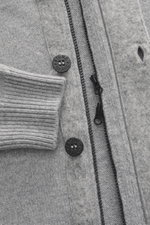 Nahaufnahme der Stone Island Strickjacke 'Lambswool' grau meliert mit Wollmix, Linksstrick, Knöpfen, Reißverschluss, Filz-Details und Rippbündchen.