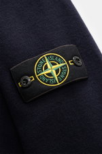 Nahaufnahme der schwarzen Stone Island Strickjacke 'Stretchwool' mit Kompass-Badge, feinem Wollmix und strukturierter Oberfläche.