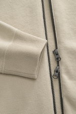 Nahaufnahme der Stone Island Strickjacke 'Stretchwool' sand, Front mit Reißverschluss und Rippbündchen, weicher Wollmix, sichtbare Details