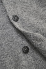 Nahaufnahme des Stone Island Cardigans grau meliert von oben, zeigt weichen Griff, mittelfeines Strickbild, Vier-Knopf-Leiste und Kompass-Badge.