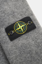 Nahaufnahme des Stone Island Cardigans grau meliert von schräg oben, mit Kompass-Badge am Oberarm, mittelfeinem Strickbild, weichem Griff, Mix aus Alpaka, Schurwolle und Microfaser.